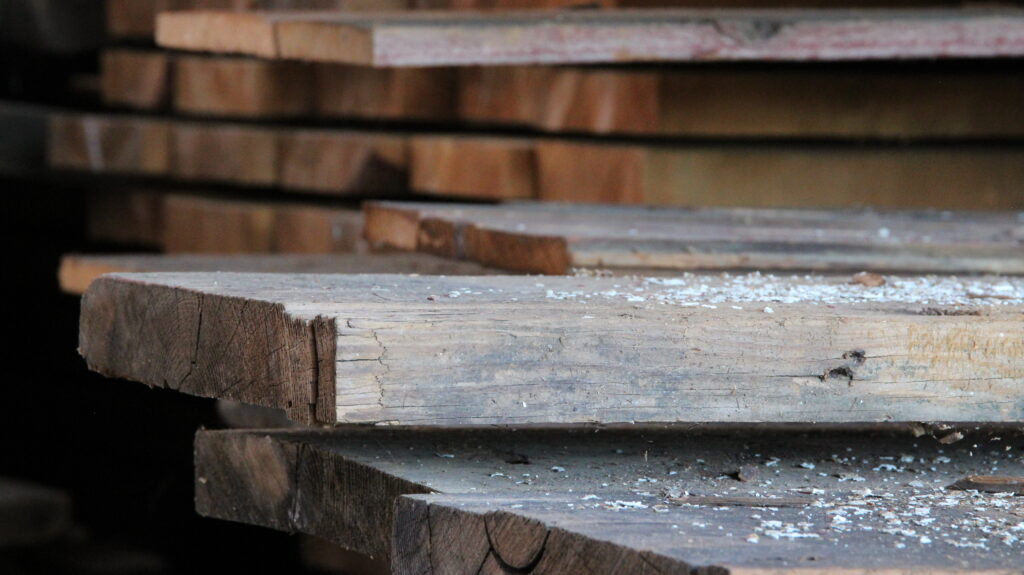 Reclaimed barn wood in factory waiting to be cut into shelves for interior home decor